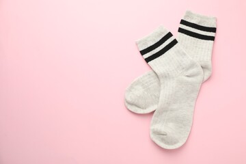 Pair of soft comfortable socks on light pink background, top view. Space for text