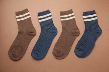 Different comfortable socks on brown background, flat lay