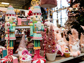 Selective focus view of beautiful Christmas display, including giant nutcracker soldiers, pink trees and cute elves in different pastel colours