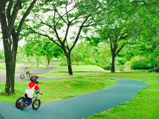 4 years old boy in safety helmeriding balance bike at summer park green trees enjoy happy childhood. .Kids on bicycle in sunny park. Sport for kids.