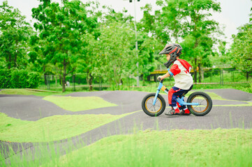 4 years old boy in safety helmeriding balance bike at summer park green trees enjoy happy childhood. .Kids on bicycle in sunny park. Sport for kids.