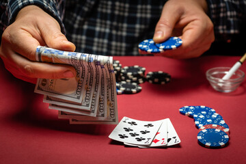 A lucky player bets money on a winning combination of cards three of a kind or set in a casino. A successful poker game with a big win and chips on a red table