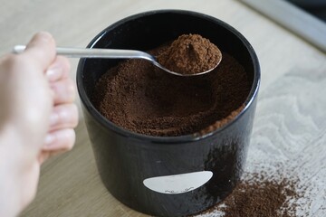 woman hand hold spoon with ground coffee spilled 