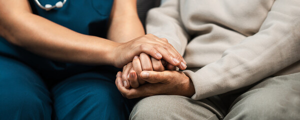 A female nurse caregiver holds hands to encourage and comfort an elderly woman. For care and trust...