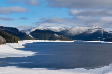 Lake Vidra on a sunny winter day with snow in Romania