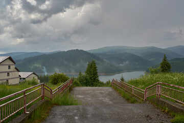 Fototapeta premium Lake Vidra seen from Vidra resort, Valcea with pine forests after rain and fog in Romania