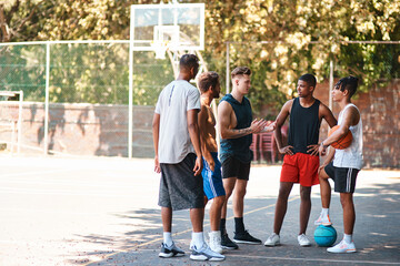 Basketball, group and men outdoor on sport court with friends, discussion and exercise break. Fitness, team and diversity with workout and training for game with teamwork together and conversation