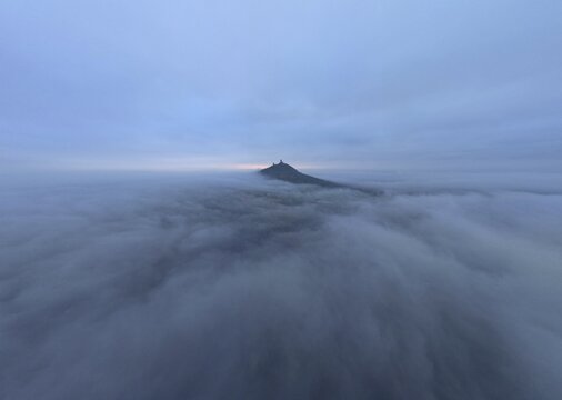 Breathtaking drone air view on Hazmburk (Hasenburg) old medieval castle on solitary hill in Central Bohemian Uplands (Ceske stredohori), Czech Republic, Europe. Foggy cloudy morning skyline panorama.