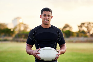 Rugby, portrait and happy man with ball for game, sports and competition at pitch at sunset. Player, smile and confident athlete at field for body health, exercise and fitness outdoor in Argentina