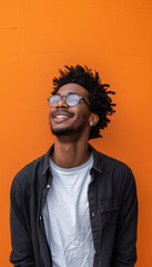 Obraz premium Playful Young Man with Mischievous Grin Against Vibrant Orange Background for Creative Design