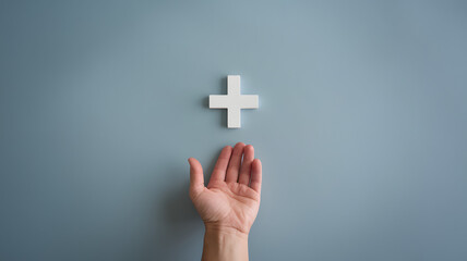Obraz premium A hand reaching towards a white plus symbol on a light blue wall in a minimalist indoor space