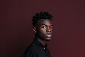 Obraz premium Focused Young Man Against Maroon Background: Intensity and Ambition for Portrait Art and Design