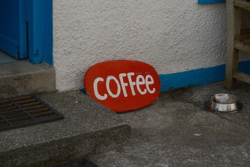 Red coffee sign outside rustic cafe 