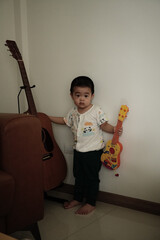Asian boy holding little acoustic guitar