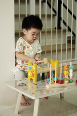 Asian boy playing wooden hammer on table at home