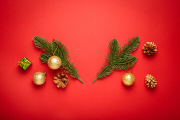 Elegantly arranged in a shape of deer antlers golden christmas balls, pine cones, fir branches, and a wrapped gift box on a red background, creating a festive holiday atmosphere