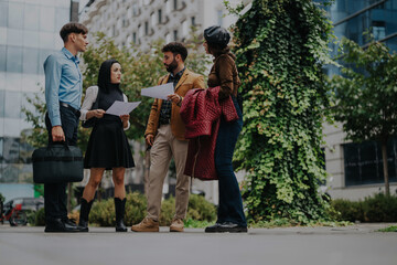 Fototapeta premium A group of business professionals engaged in an outdoor meeting, discussing project documents and strategies in an urban environment. The setting reflects a collaborative and analytical atmosphere.