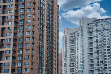 Fototapeta premium View of modern high rise residential buildings in Shanghai, China, featuring diverse architectural styles and a partly cloudy sky.