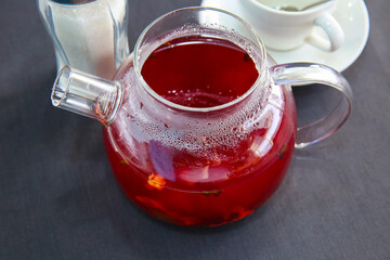 Red hot fruit tea brewed in a glass teapot