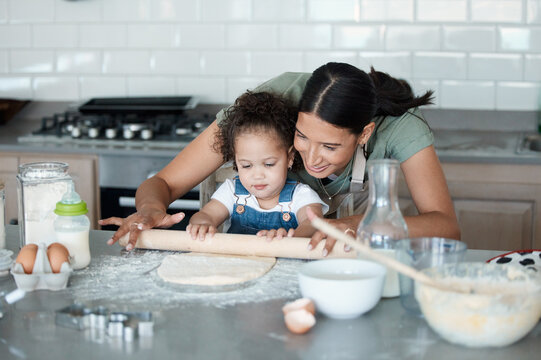 Happy mother, kid and learning baking with rolling pin for dough, flour and toddler in kitchen. Mom, child and cooking with parent, help and teaching girl dessert recipe for support in family home - Powered by Adobe