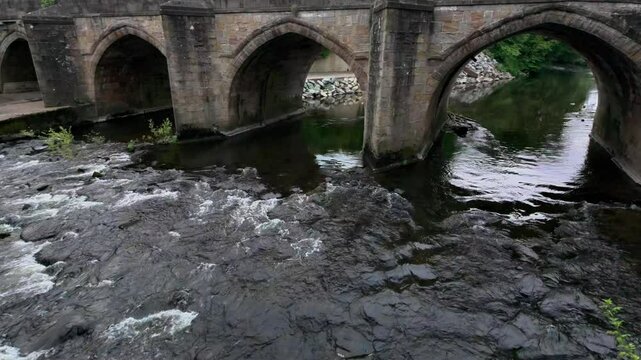 River Derwent flowing under Matlock Derwent Bridge in slow-motion at the daytime in Derbyshire, UK