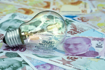 Increase in Electricity Prices. Macro detail shot of burning light bulb on representative Turkish lira.