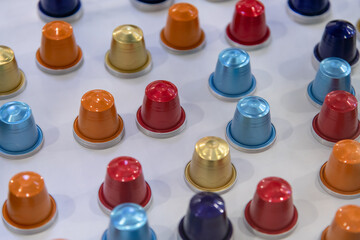 Close-up view of group of various multi coloured empty aluminium packages for coffee capsules (or coffee pods) lying on grey table. Coffee tool background. Copy space. Recyclable material theme.