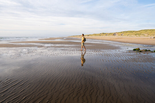 Man figure on the North sea beach with the sandy dunes in the background not far from Den Helder town in the province of North Holland, the Netherlands