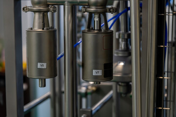 Close-up view of parts and pipes of milk pasteurization and cooling machine. Industrial background. Soft focus. Copy space. Food and drink processing equipment theme.