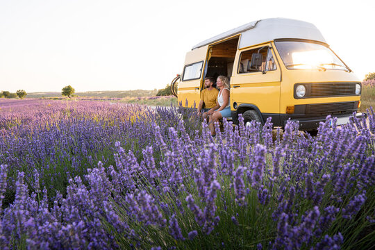 Young happy couple enjoying the view in their retro camper van at sunrise in Valensole lavender fields in Provence, France. Happiness and freedom lifestyle