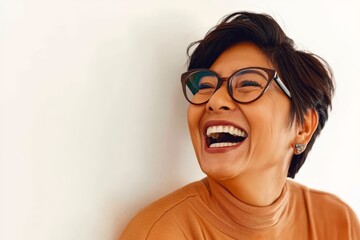 Woman with short hair and glasses laughing joyfully against a bright background, showcasing a sense of humor, warmth, and infectious positivity in her expression.