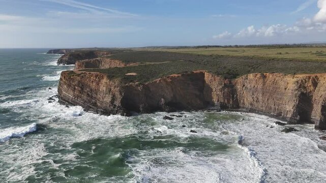 Drone ascends above huge coastal cliffs and giant ocean surf. Alentejo region, Portugal 