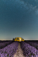 Retro yellow camper van parked under the starry sky in Valensole lavender fields in Provence, France. Long exposure astrophotography