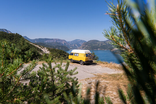 Retro camper van parked on the cliffs with the view of Serre-Poncon lake, Ecrins national park, France