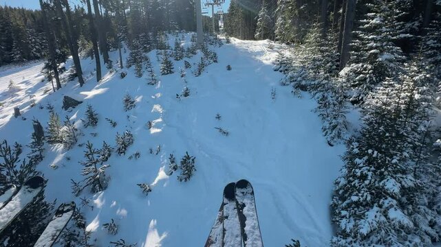Skier man pov running on chairlift ski lift at skiing adventure down snowy slopes in Bansko, Bulgaria
