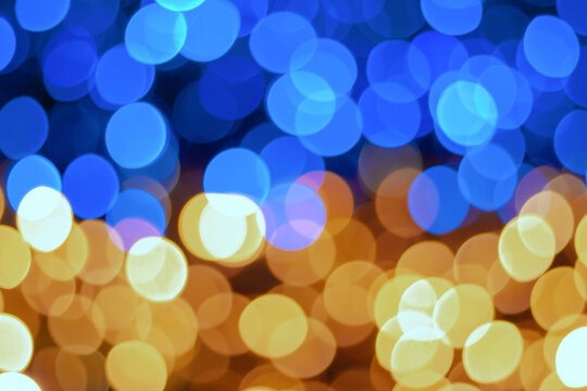 Abstract bokeh background with yellow and blue circular lights softly blending into each other, creating a vibrant, festive atmosphere with a subtle gradient from warm to cool tones.
