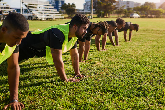 Men, rugby players or grass field with push ups for fitness training, team practice or workout at outdoor stadium. Male people, group or athletes with exercise, preparation or getting ready for sport