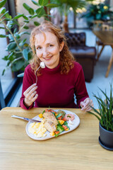 Joyful woman enjoying healthy brunch at cozy cafe indoors