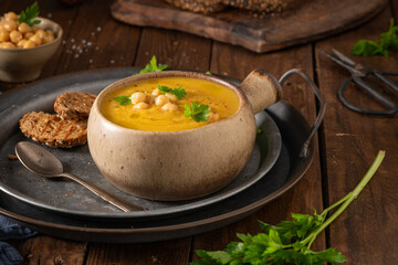 Pumpkin and chickpeas soup on brown rustic wooden background.