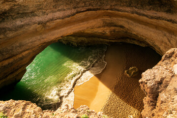 A top-down view of Benagil Cave in Portugal, revealing turquoise waters and a sandy beach through...