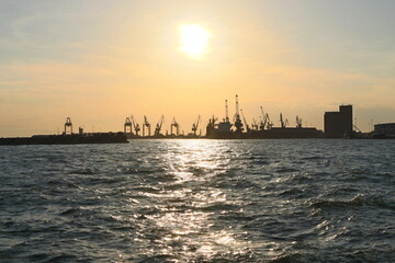 Naklejka premium Industrial Port Cranes Silhouetted Against Sunset on the Waterfront