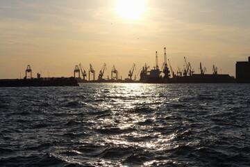 Naklejka premium Industrial Port Cranes Silhouetted Against Sunset on the Waterfront