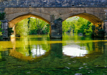 Fototapeta premium Close up of two arches of the bridge that are reflected in the water of the Zrmanja river, Croatia