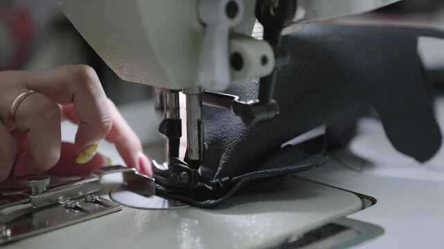 hands seamstress sew product from leather fabric sewing machine. concept female business work home. tailor sews high quality fabric. concept work private leather workshop motion. needle process sewing