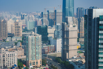 Fototapeta premium The image depicts Shanghai's dense skyline, featuring a tall cylindrical skyscraper, construction cranes, and a Ferris wheel in the background.