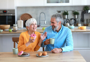 breakfast woman man senior couple home wife husband elderly together happy morning old happiness sharing food donut dessert love mature eating