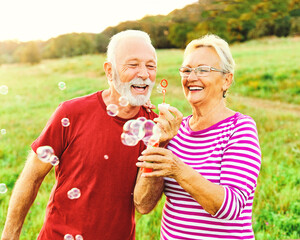 Fototapeta premium woman man outdoor senior couple happy fun retirement together bubble soap blowing love old nature mature