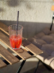Refreshing glass of red fruit juice with a straw on a wooden table