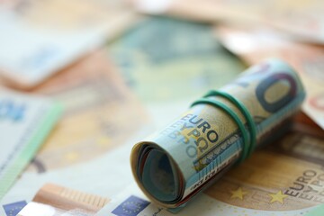 Roll of twenty euro currency bills lies on big amount of hundred and fifty euro banknotes