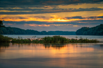 Sunrise idyll landscape on a river with a cloudy sky at golden hour